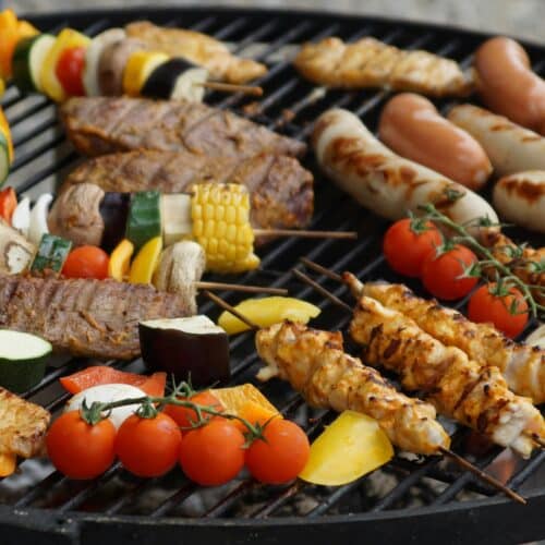 A vibrant assortment of grilled meats, sausages, and vegetables on a barbecue grill.